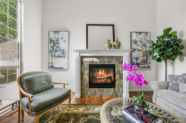 living room featuring a high end fireplace, wood finished floors, and healthy amount of natural light