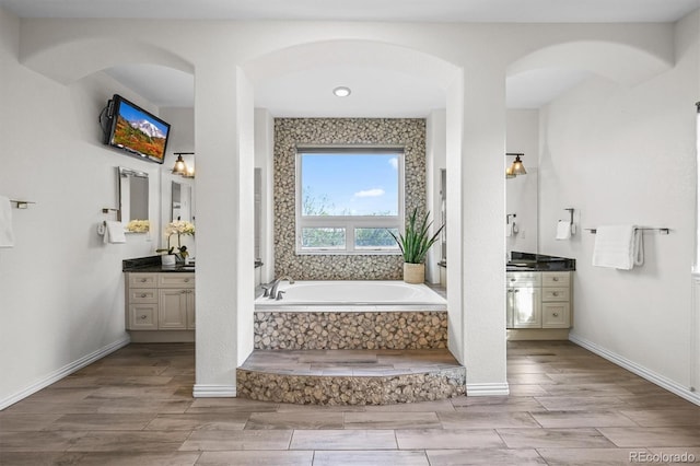bathroom with wood tiled floors, a bath, and vanity