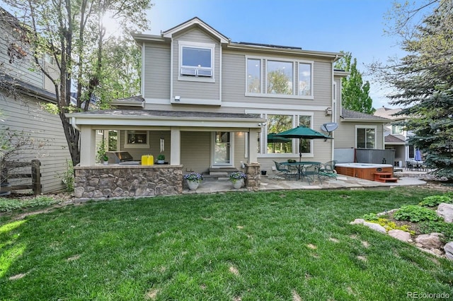 rear view of house with a hot tub, a patio, and a yard