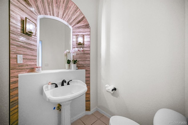 half bath with toilet, tile patterned flooring, and baseboards