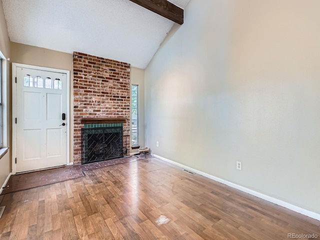 1990 S Helena St Unit H, Aurora, CO 80013 - unfurnished living room featuring wood finished floors, beamed ceiling, a fireplace, and high vaulted ceiling