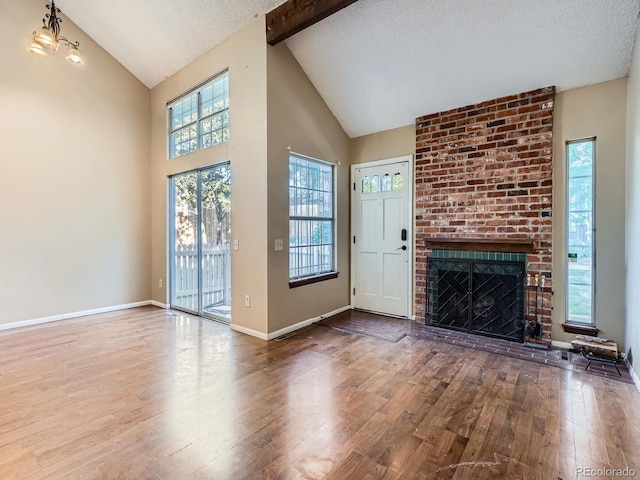1990 S Helena St Unit H, Aurora, CO 80013 - unfurnished living room with wood-type flooring, a brick fireplace, high vaulted ceiling, beam ceiling, and a textured ceiling