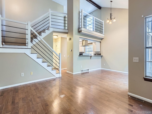 1990 S Helena St Unit H, Aurora, CO 80013 - unfurnished living room featuring a chandelier, stairway, wood finished floors, beamed ceiling, and high vaulted ceiling