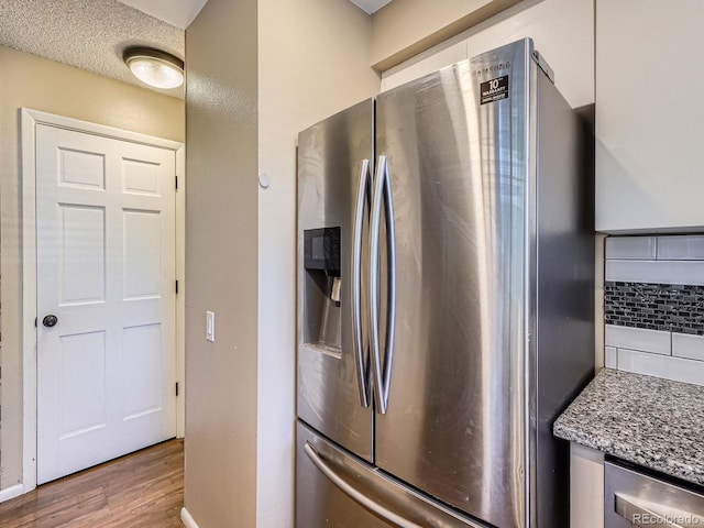 1990 S Helena St Unit H, Aurora, CO 80013 - kitchen featuring stainless steel fridge with ice dispenser, wood finished floors, decorative backsplash, and light stone countertops