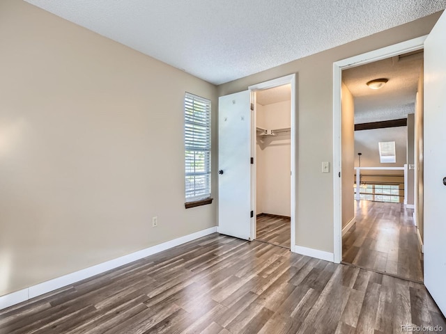 1990 S Helena St Unit H, Aurora, CO 80013 - unfurnished bedroom with dark wood-style floors, a textured ceiling, and a walk in closet