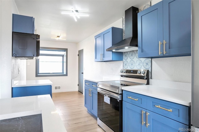 kitchen with electric stove, wall chimney exhaust hood, and blue cabinets