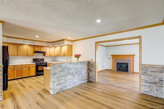 200 E 6th St, Flagler, CO 80815 - kitchen with black appliances, under cabinet range hood, a textured ceiling, a peninsula, and light countertops