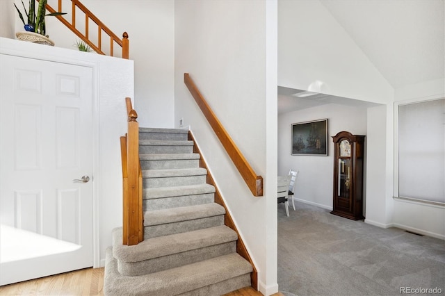 staircase with carpet flooring and high vaulted ceiling