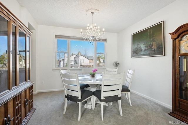 dining area featuring a textured ceiling, light colored carpet, and an inviting chandelier