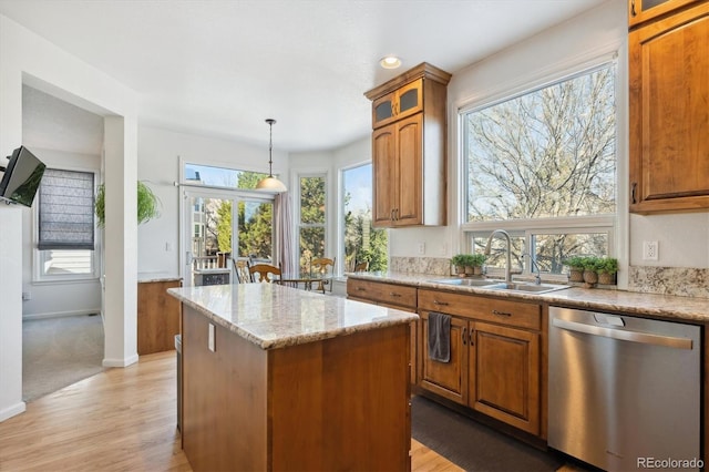 kitchen with light wood-type flooring, stainless steel dishwasher, a kitchen island, and sink