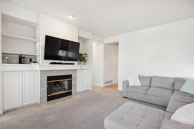 living room featuring a tile fireplace, light carpet, and a textured ceiling