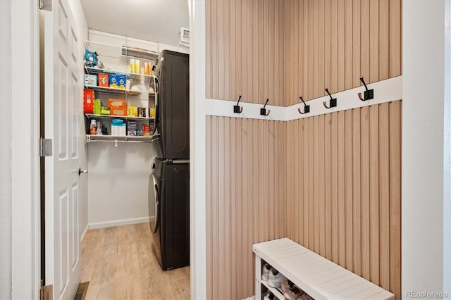 mudroom featuring stacked washer / drying machine and light hardwood / wood-style flooring