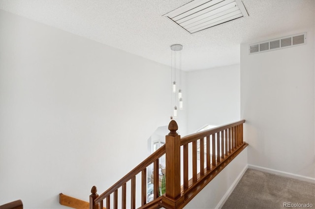 stairs with carpet and a textured ceiling