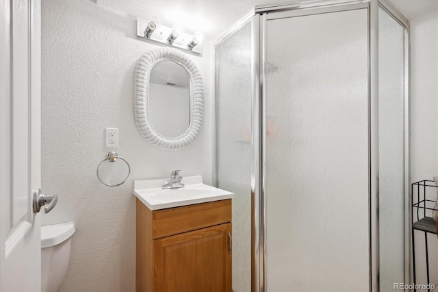 bathroom featuring an enclosed shower, vanity, and toilet