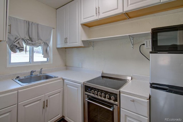 1560 Simms St, Lakewood, CO 80215 - kitchen featuring range with electric cooktop, a sink, white cabinetry, freestanding refrigerator, and light countertops