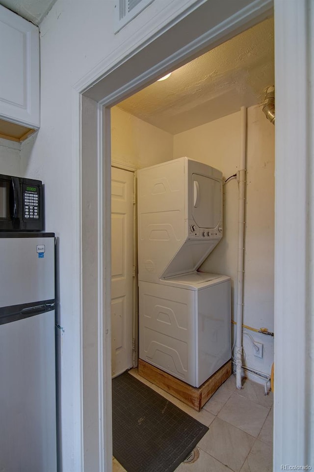 1560 Simms St, Lakewood, CO 80215 - washroom with stacked washer and clothes dryer and light tile patterned floors