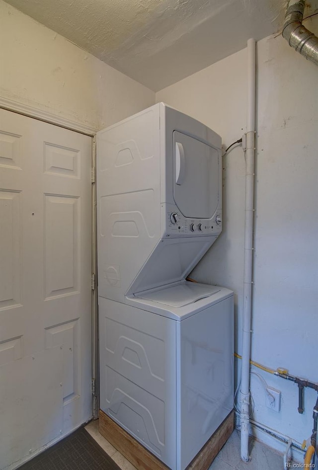 1560 Simms St, Lakewood, CO 80215 - laundry room featuring stacked washer / dryer and tile patterned floors