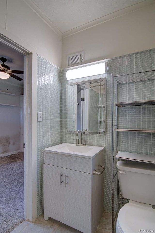 1560 Simms St, Lakewood, CO 80215 - bathroom featuring tile walls, ornamental molding, vanity, toilet, and ceiling fan