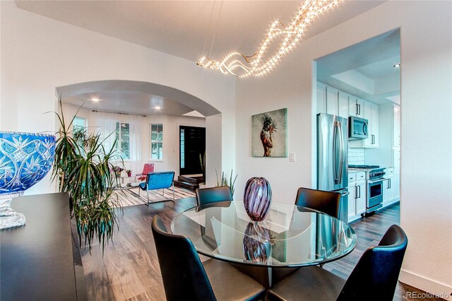 dining space with hardwood / wood-style floors and an inviting chandelier