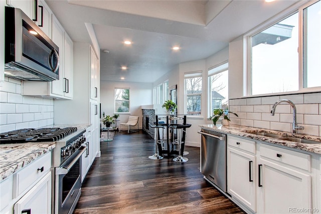 kitchen featuring sink, dark hardwood / wood-style floors, decorative backsplash, appliances with stainless steel finishes, and white cabinetry