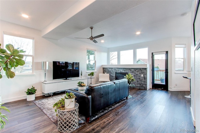 living room featuring dark hardwood / wood-style floors, ceiling fan, and a tiled fireplace