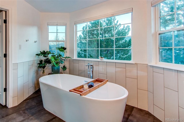 bathroom featuring a washtub, wood-type flooring, and tile walls