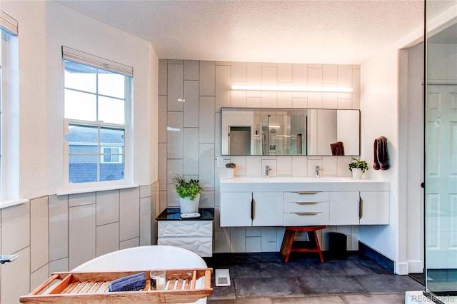 bathroom featuring vanity, a tub to relax in, and a textured ceiling