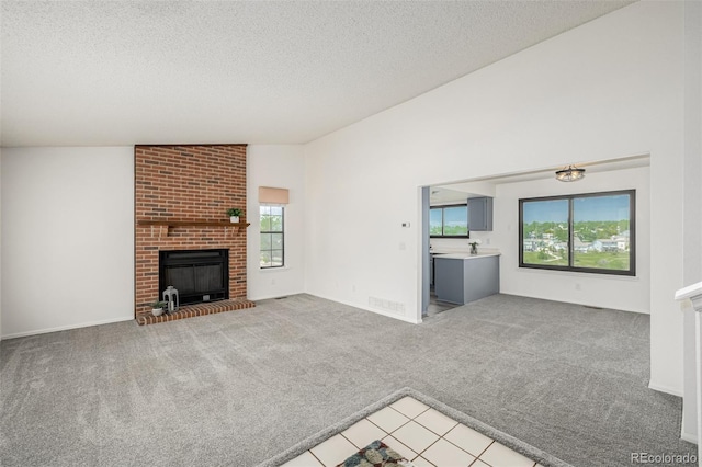 551 Snowy Owl Pl, Highlands Ranch, CO 80126 - unfurnished living room featuring light colored carpet, a textured ceiling, a fireplace, and light tile patterned flooring