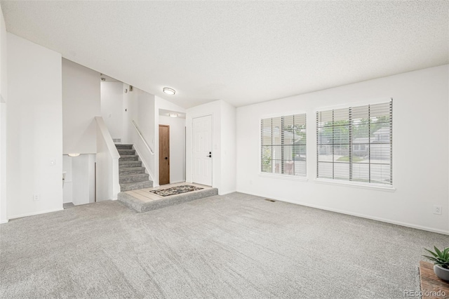 551 Snowy Owl Pl, Highlands Ranch, CO 80126 - unfurnished living room with stairs, carpet, a textured ceiling, and vaulted ceiling