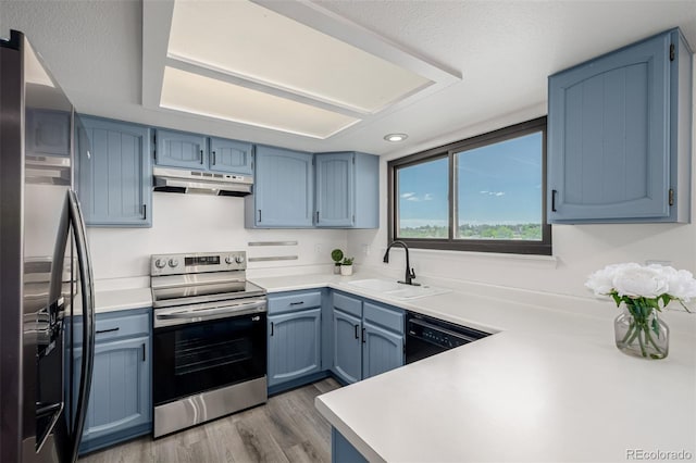 551 Snowy Owl Pl, Highlands Ranch, CO 80126 - kitchen featuring appliances with stainless steel finishes, under cabinet range hood, blue cabinetry, light wood finished floors, and light countertops
