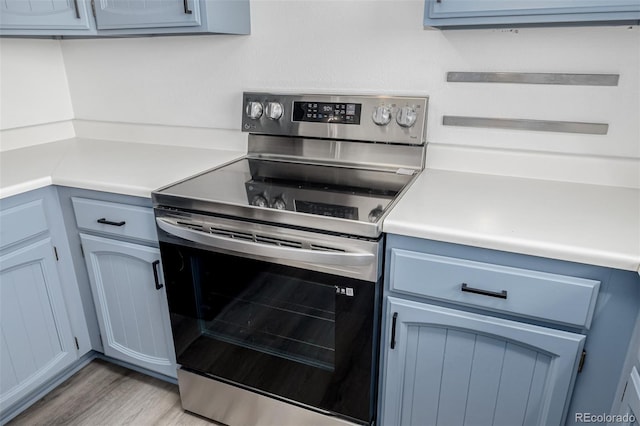 551 Snowy Owl Pl, Highlands Ranch, CO 80126 - kitchen with stainless steel range with electric cooktop, light countertops, light wood-style floors, and blue cabinetry