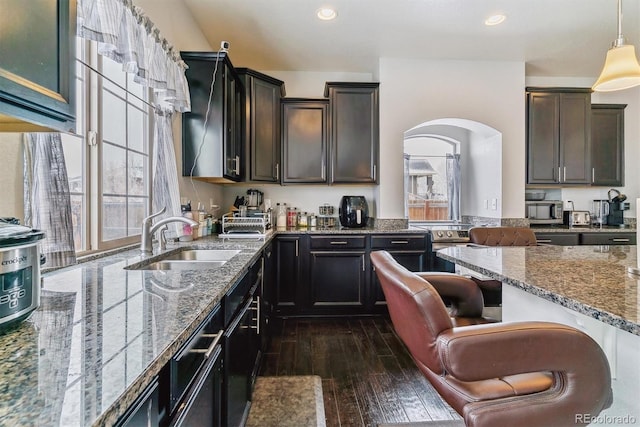 kitchen with dark wood finished floors, a sink, dark brown cabinetry, and pendant lighting