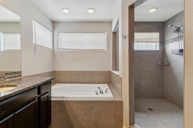 bathroom with recessed lighting, a garden tub, a tile shower, and vanity