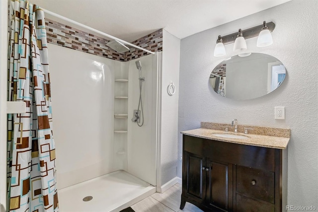 bathroom featuring a textured wall, a shower stall, and vanity