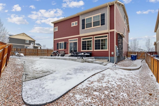 snow covered property featuring entry steps and a fenced backyard