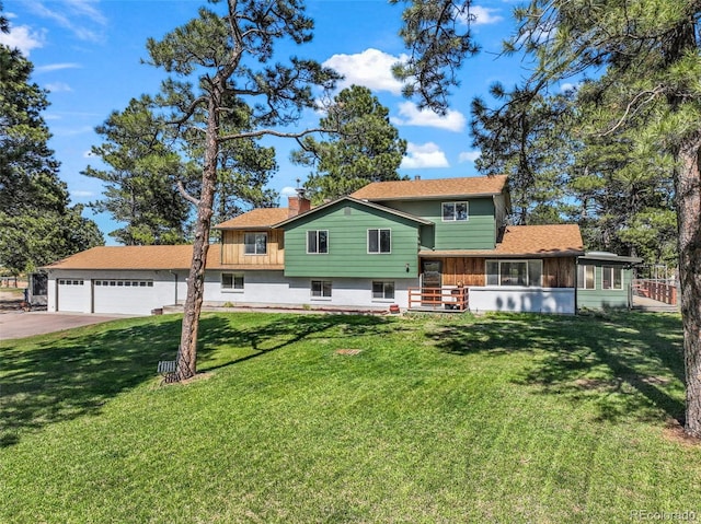 split level home featuring concrete driveway, a chimney, a front yard, a sunroom, and an attached garage