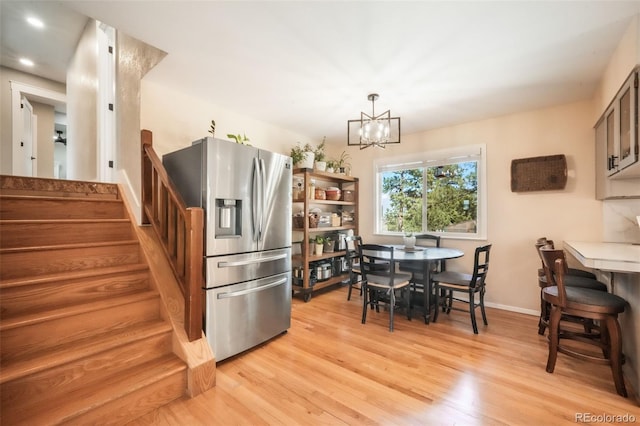 kitchen with stainless steel refrigerator with ice dispenser, a chandelier, light wood-style floors, recessed lighting, and baseboards