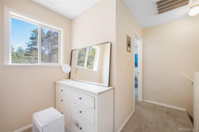 hallway with baseboards and light colored carpet