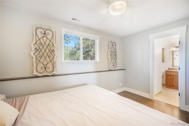 unfurnished bedroom featuring wood finished floors, baseboards, connected bathroom, and ceiling fan
