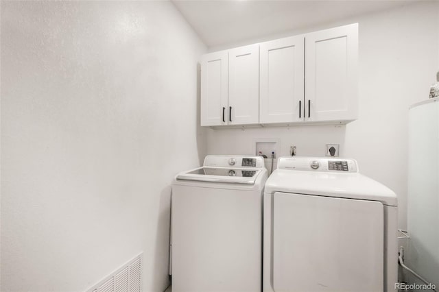 washroom with cabinet space, independent washer and dryer, and water heater