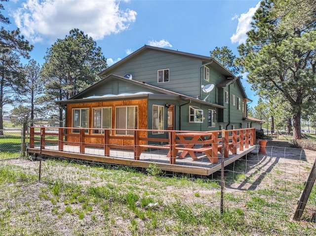 rear view of house with a wooden deck and fence