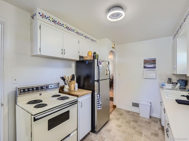 kitchen with tasteful backsplash, sink, electric range, white cabinets, and stainless steel refrigerator