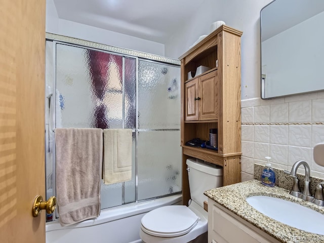 full bathroom featuring toilet, backsplash, vanity, tile walls, and enclosed tub / shower combo