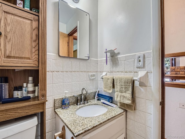 bathroom with vanity, toilet, and tile walls