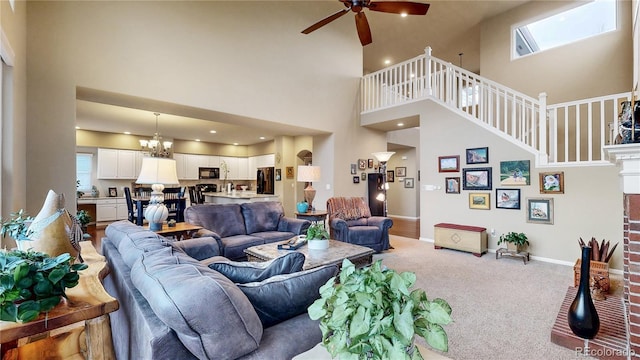 carpeted living area with ceiling fan with notable chandelier and baseboards