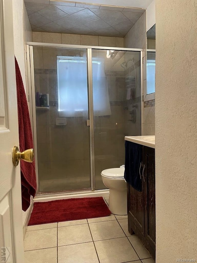 bathroom featuring tile patterned flooring, vanity, toilet, and an enclosed shower