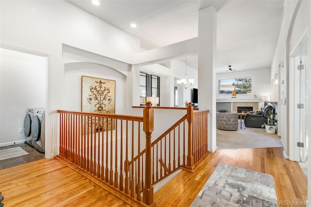 corridor with an inviting chandelier, light hardwood / wood-style floors, and independent washer and dryer