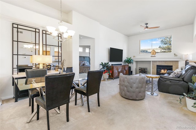 dining room with a fireplace, carpet, and ceiling fan with notable chandelier