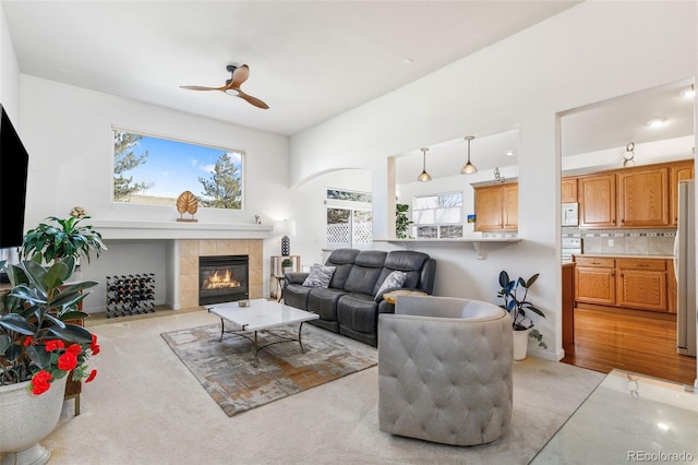 carpeted living room with a tiled fireplace, ceiling fan, and a towering ceiling