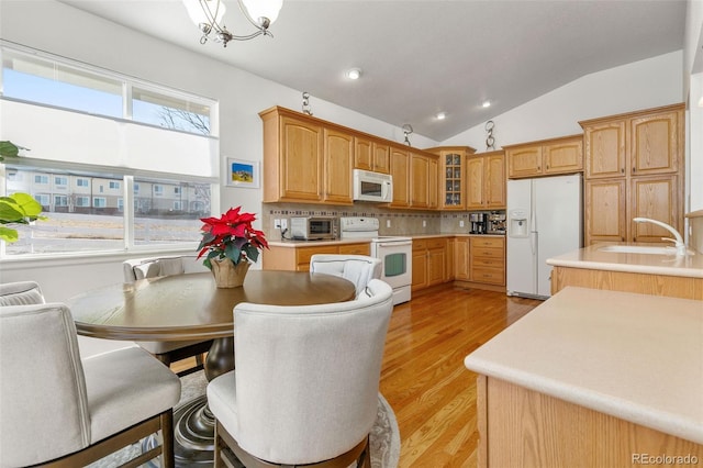 kitchen with decorative backsplash, white appliances, sink, a chandelier, and hanging light fixtures